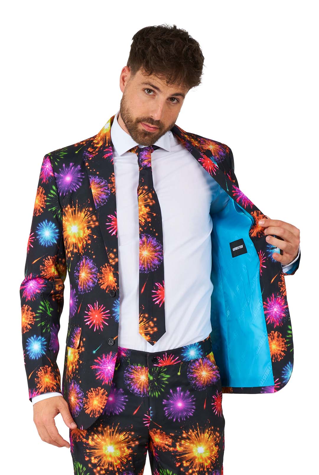 A man dressed in Suitmeister's Fireworks Black ensemble, featuring a vibrant fireworks pattern with a coordinating tie, opens the jacket to reveal a light blue lining as he stands against a white backdrop.