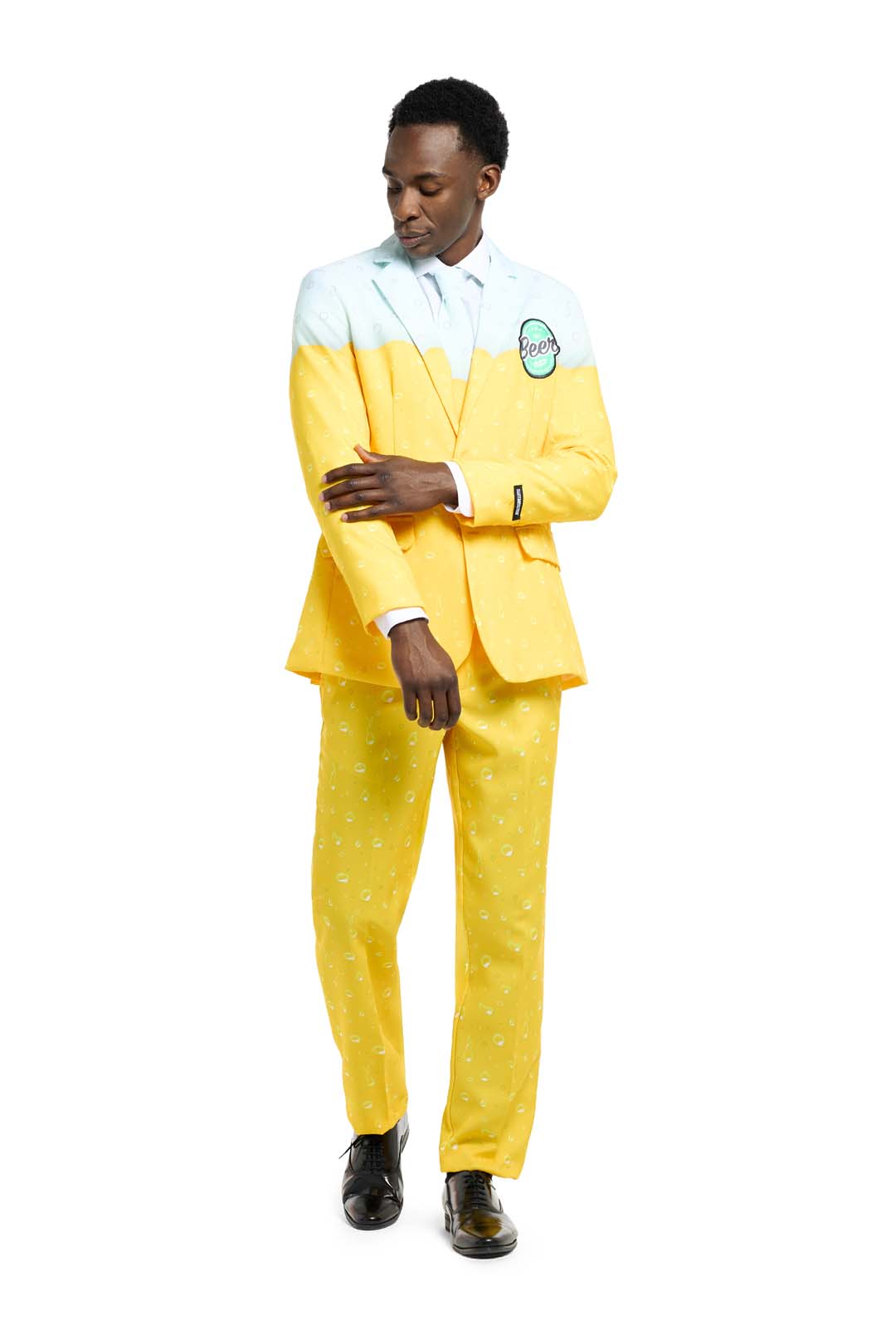 A man wearing the "Premium Beer Yellow" suit by Suitmeister, featuring a bright yellow and white beer-themed design with a matching tie. He is adjusting his sleeve while standing against a plain white background.