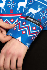 Close-up of a hand adjusting the sleeve of a Blue Nordic Jacket adorned with a festive holiday design featuring white reindeer, red and white geometric shapes. The jacket is by Suitmeister.