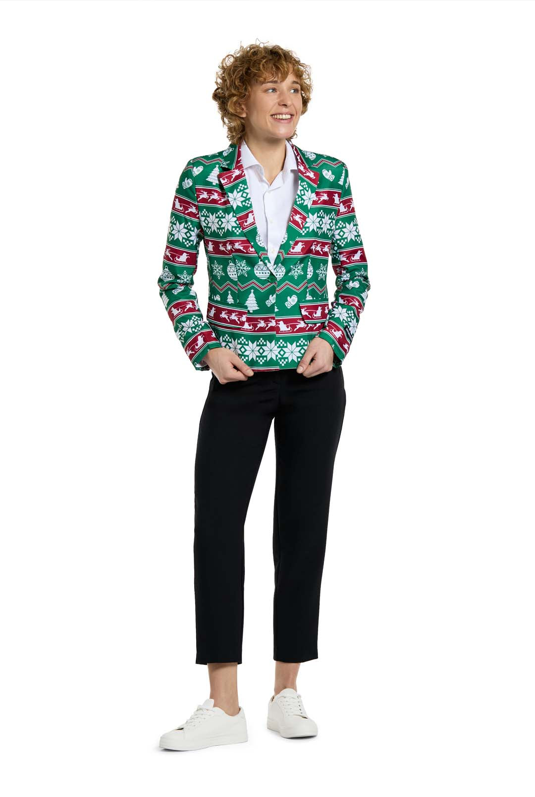 A person with curly hair smiles while wearing the Suitmeister Christmas Green Nordic Jacket, a festive blazer with holiday-themed patterns, along with a white shirt, black pants, and white sneakers, standing against a white background.