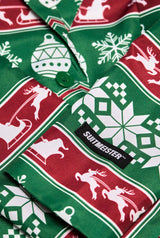 Close-up of a festive fabric featuring red and green Christmas-themed patterns, including reindeer, snowflakes, and ornaments. The label on the fabric reads "Suitmeister," associated with the Christmas Green Nordic Jacket - a Christmas blazer.