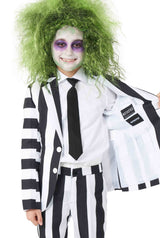 A child is dressed in a Suitmeister Beetlejuice suit, featuring a black and white striped jacket paired with a matching tie. They are displaying the inside lining of the jacket while sporting exaggerated green hair and ghostly face paint.