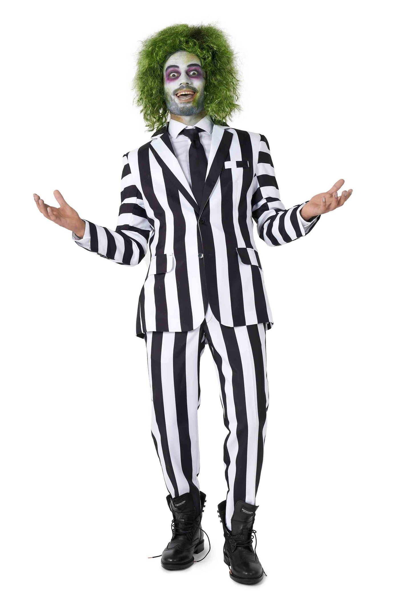 A person wearing the Suitmeister Beetlejuice costume stands with arms outstretched, smiling mischievously. They have green, messy hair and pale face makeup with dark eye circles, resembling a classic movie character.