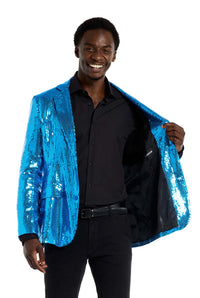 A person smiles while wearing a shimmering Suitmeister Sequins Blue Blazer over a black shirt and pants. They are holding the blazer open slightly to reveal the lining, set against a plain white background.