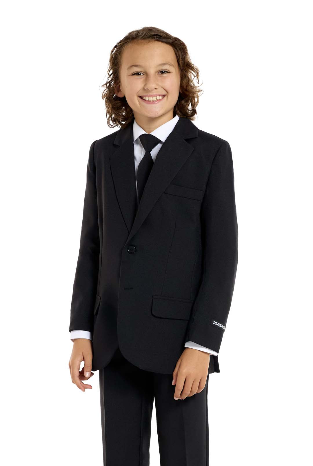 A young person with long hair, smiling, is wearing Suitmeisters Solid Black suit paired with a white shirt and black tie, standing against a white background.