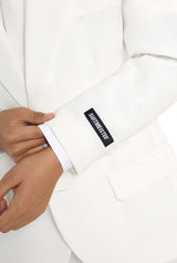 Close-up of a person adjusting the left sleeve of a tailored, elegant Solid White suit by Suitmeister, with a visible black label featuring the brand name.