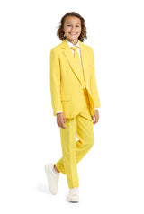 A young person with curly hair beams in a Solid Yellow Suitmeister suit, accompanied by a white shirt and sneakers. They pose against a plain white background with one hand in their pocket.