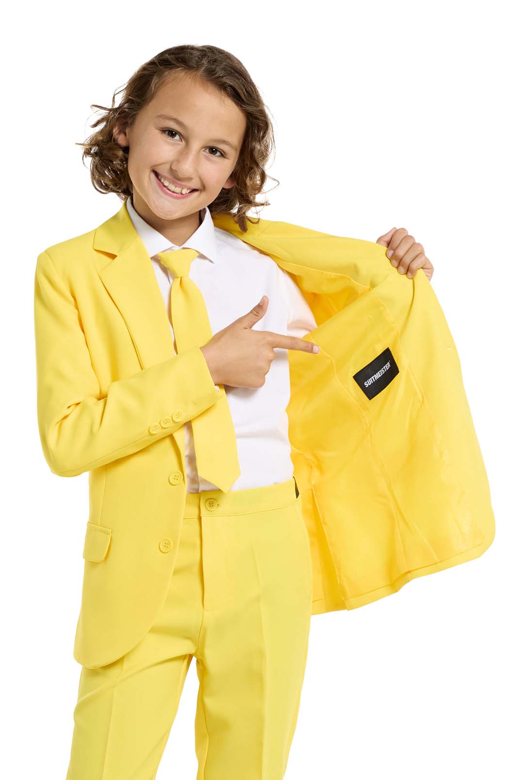 A smiling child with curly hair points to a label inside the Solid Yellow suit by Suitmeister while wearing it against a plain white background.