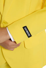 Close-up of a person in a solid yellow Suitmeister jacket, with the label visible on the sleeve near the white cuff, holding the jacket at the waist.