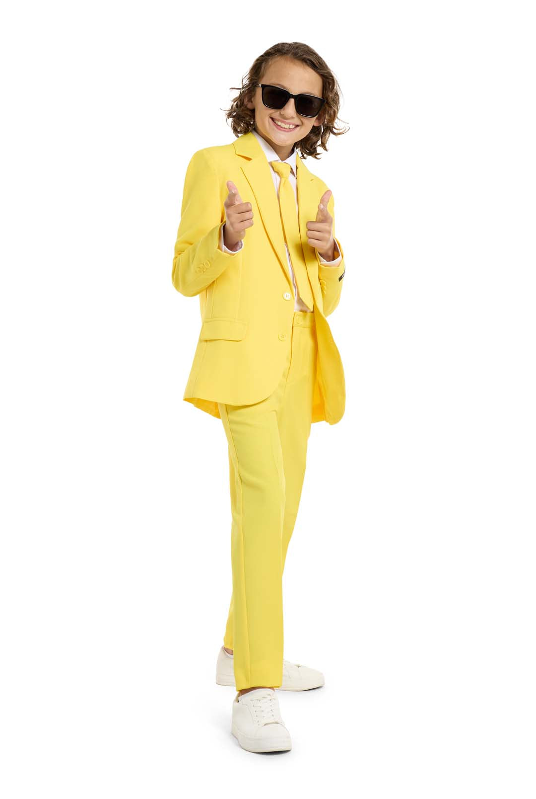 A confident child in a Solid Yellow suit from Suitmeister, paired with a white shirt, yellow tie, sunglasses, and white sneakers gives a double thumbs-up against a white background.