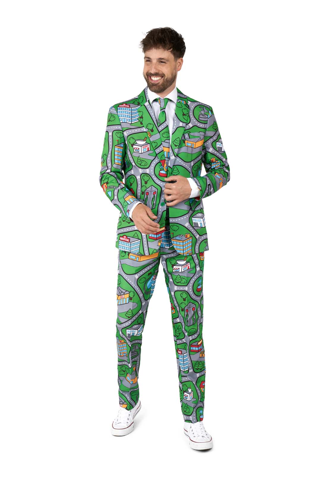 A man smiles while wearing the Suitmeister's Carpet City Green - Play Carpet suit, showcasing a playful city map design with streets and buildings in green, blue, and other vibrant colors. He pairs it with a white dress shirt, matching tie, and white sneakers.