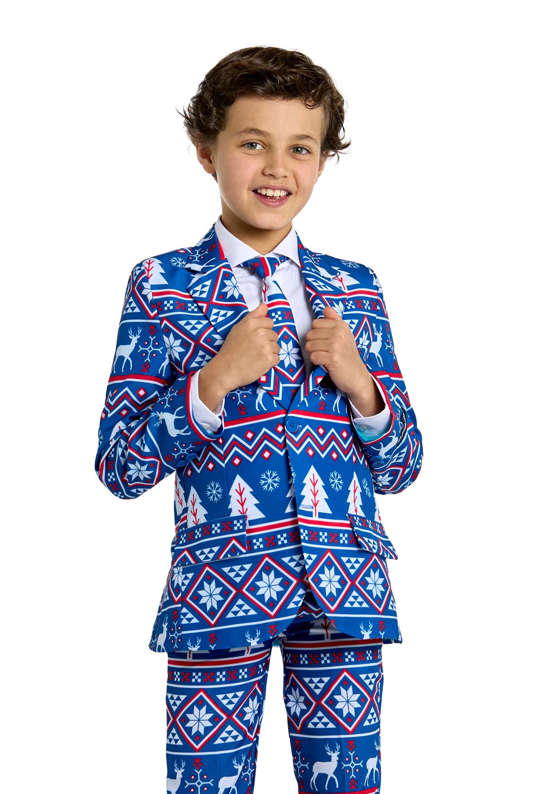 A young boy smiles while wearing the Suitmeister Christmas Suit Blue Nordic, adorned with festive red and white holiday patterns of snowflakes and reindeer, set against a plain white background.