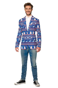 A smiling person is wearing the Christmas Blue Nordic Jacket by Suitmeister, a blue blazer with festive white and red patterns featuring reindeer and trees. They pair it with a white shirt, blue jeans, and black sneakers while standing against a white background.