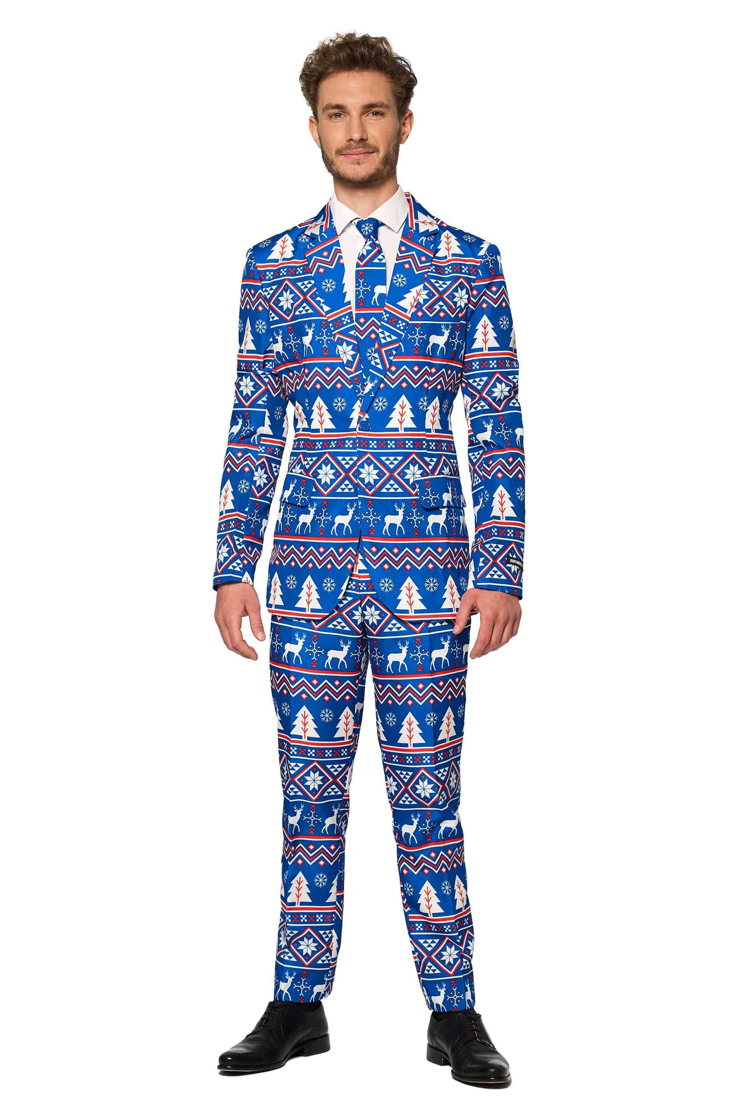 A man dressed in the "Christmas Suit Blue Nordic" by Suitmeister, featuring a festive blue design with white and red holiday patterns of snowflakes and reindeer, complemented by a white shirt and blue tie, standing against a plain white background.