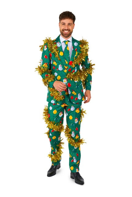 A person is wearing the "Christmas Deco Green - Ugly Christmas suit" by Suitmeister, adorned with colorful images of snowmen and ornaments, and wrapped in golden tinsel. They are smiling and posing in front of a white background.