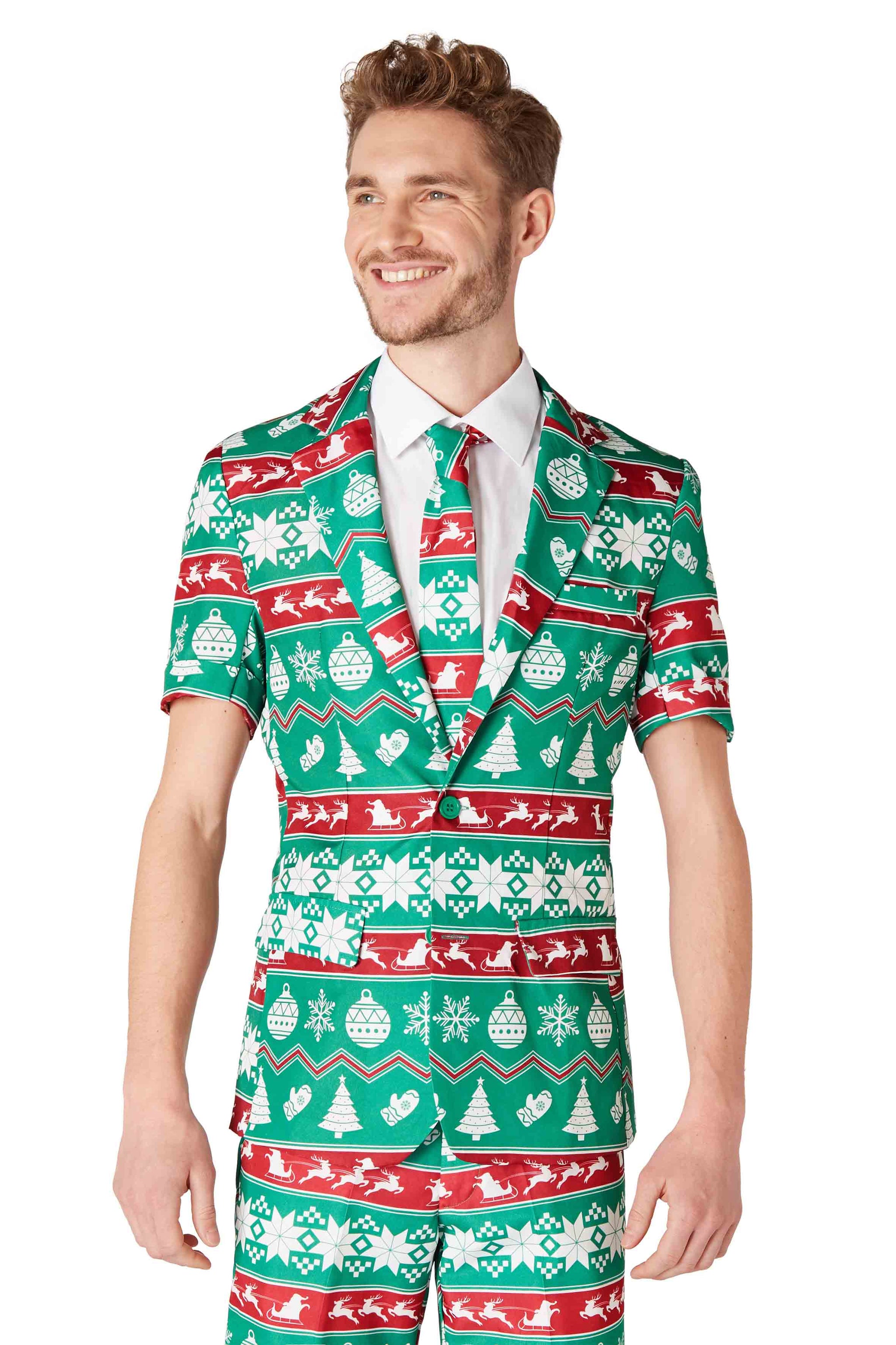 A man is dressed in a Suitmeister Christmas Green Nordic suit, showcasing a vibrant pattern of trees, snowflakes, and reindeer. He is smiling and gazing to the side, complemented by a matching tie and crisp white shirt.