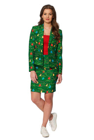 A woman is wearing the "Green trees - Christmas outfit" by Suitmeister, which features a green suit adorned with a colorful holiday-themed pattern, including ornaments. Underneath, she pairs it with a red top and white sneakers while standing against a plain white background.