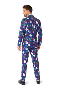 A man wearing the "Christmas Snowman Blue" suit by Suitmeister, featuring patterns of snowmen, candy canes, and Christmas decorations, stands facing away. The predominantly blue suit is adorned with colorful accents. He completes his outfit with black shoes.