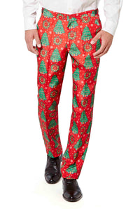 A person is dressed in a Suitmeister red Christmas suit adorned with a festive Christmas tree design, paired with a white shirt and black shoes, against a plain white background.