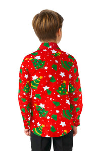 A child with light brown hair stands with their back to the camera, wearing a Suitmeister "Christmas Trees Stars Red" Christmas shirt, featuring green Christmas trees, white stars, and yellow dots. They are also wearing black pants against a white background.