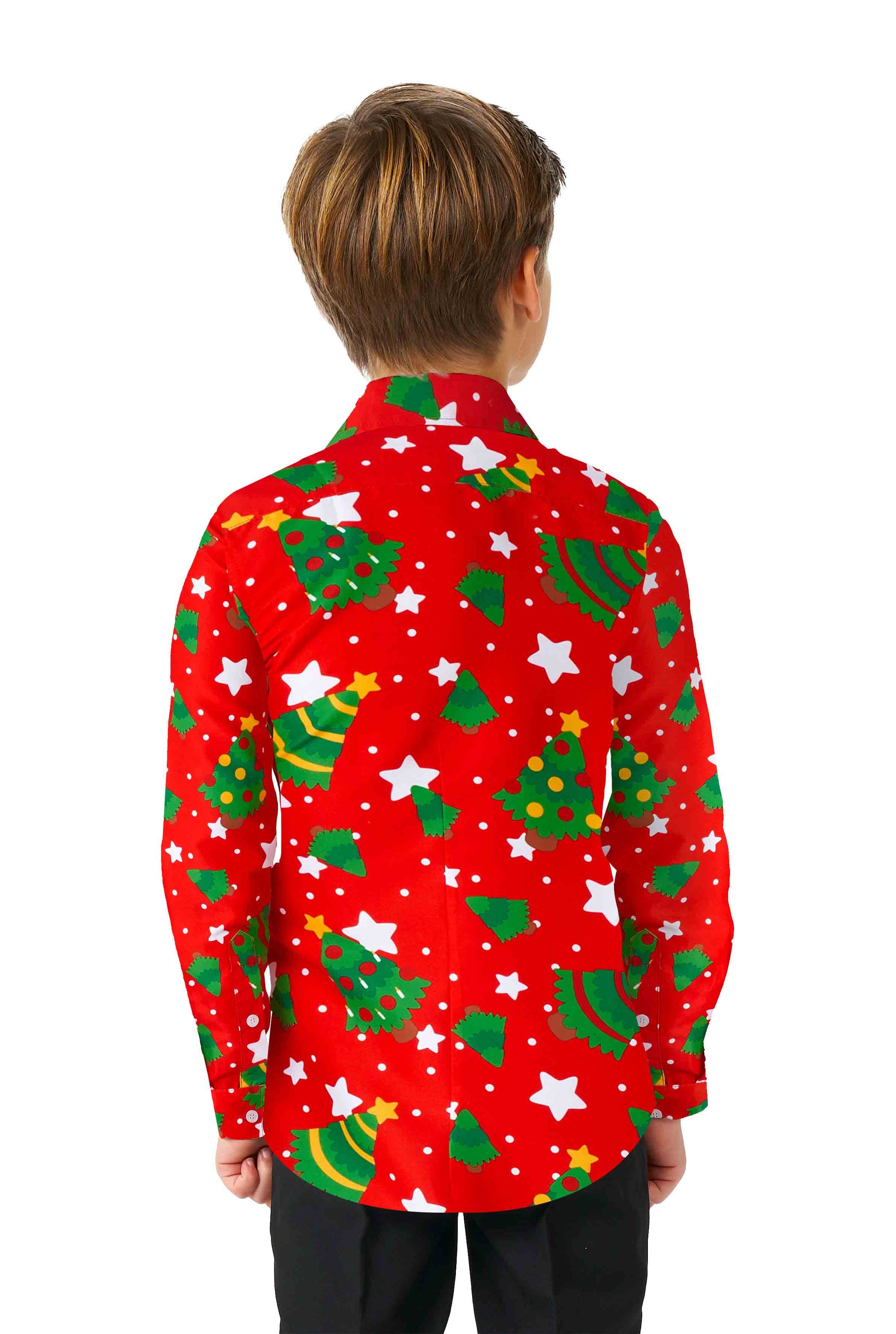 A child with light brown hair stands with their back to the camera, wearing a Suitmeister "Christmas Trees Stars Red" Christmas shirt, featuring green Christmas trees, white stars, and yellow dots. They are also wearing black pants against a white background.