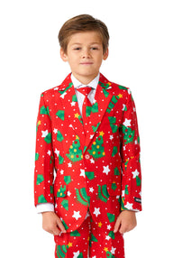 A young boy is dressed in a striking Christmas Trees Stars Red suit from Suitmeister, complete with green Christmas tree and white star patterns. He's paired it with a crisp white shirt and a red tie, his hair neatly styled as he stands against a plain white background.