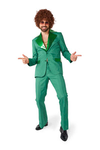 A person dressed in the Suitmeister Disco Suit Green, featuring a shiny lapel and paired with a green shirt, strikes a playful pose while wearing a curly wig and sunglasses, with fingers pointing outward.