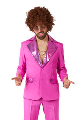 A man confidently smiles while pointing his fingers, dressed in Suitmeister's Disco Suit Pink featuring sequined lapels. He's accessorized with sunglasses, a curly wig, and a gold chain necklace, perfectly capturing the 70s disco vibe against a white background.