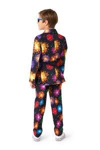 A young boy stands with his back to the camera, dressed in a dynamic Suitmeister outfit called the Fireworks Black - NYE suit. He sports short, light brown hair and blue sunglasses, all set against a plain white background.