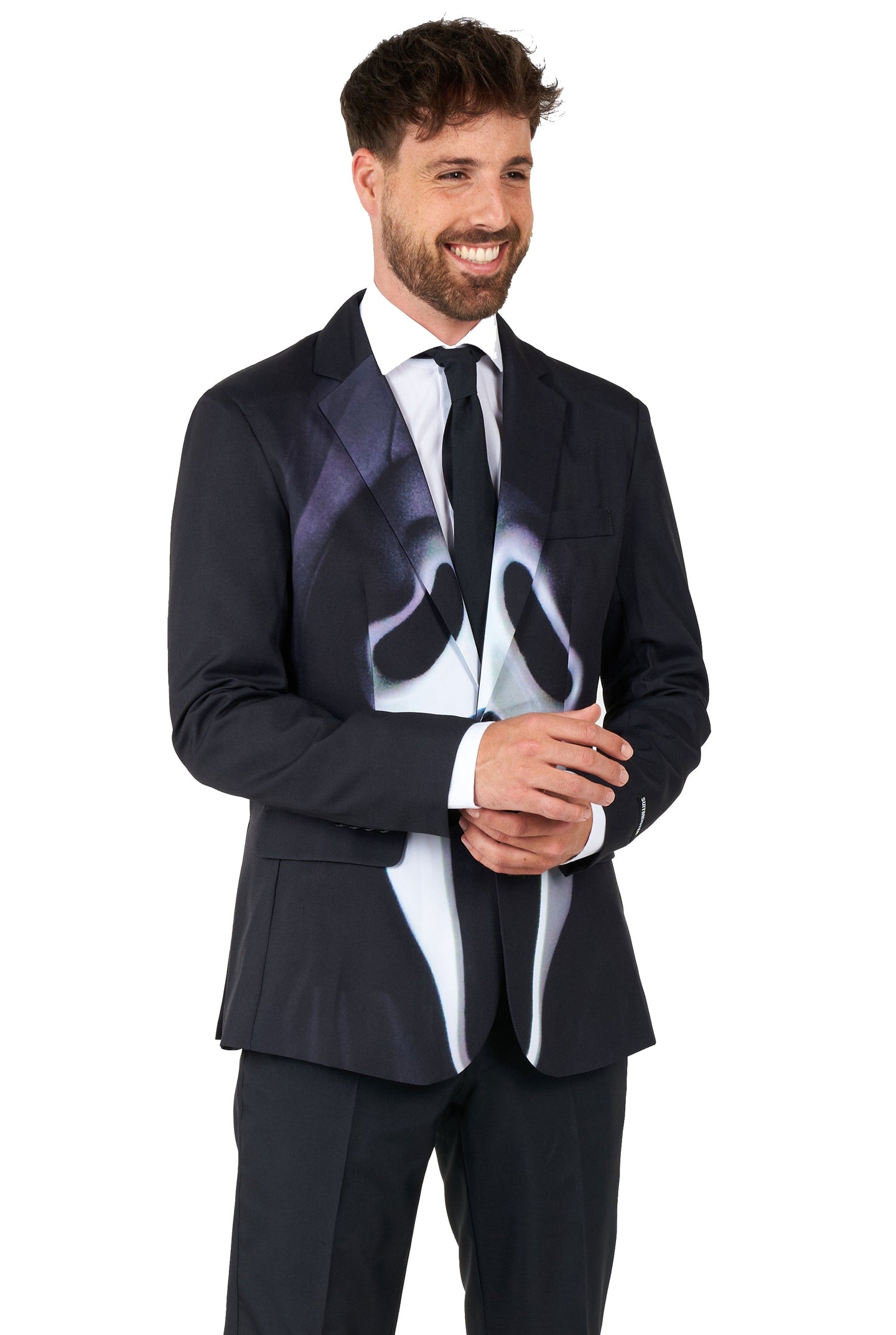 A man smiling and wearing Suitmeister's Ghostface suit, which includes a black jacket with a graphic design resembling a ghostly face, paired with a white shirt and tie. The background is plain white.