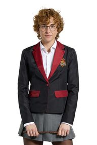 A person with curly hair and glasses is dressed in a Suitmeister Harry Potter Gryffindor™ Blazer, featuring a black design with red accents, paired with a white shirt and gray skirt. They hold a wand-like stick against a plain white background.