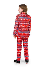 A child stands facing slightly away, dressed in the Suitmeister Nordic Pixel Red Christmas suit, featuring white and blue patterns with snowflakes and reindeer. The outfit includes a matching pair of pants and jacket, complemented by black and white sneakers.