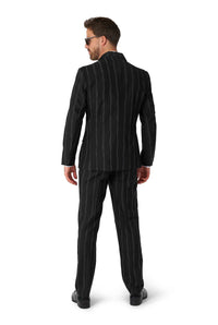 A man wearing the Oversized Pinstripe Black suit from Suitmeister stands facing away. With sunglasses on and short hair, he exudes a formal and stylish look against a plain white background.