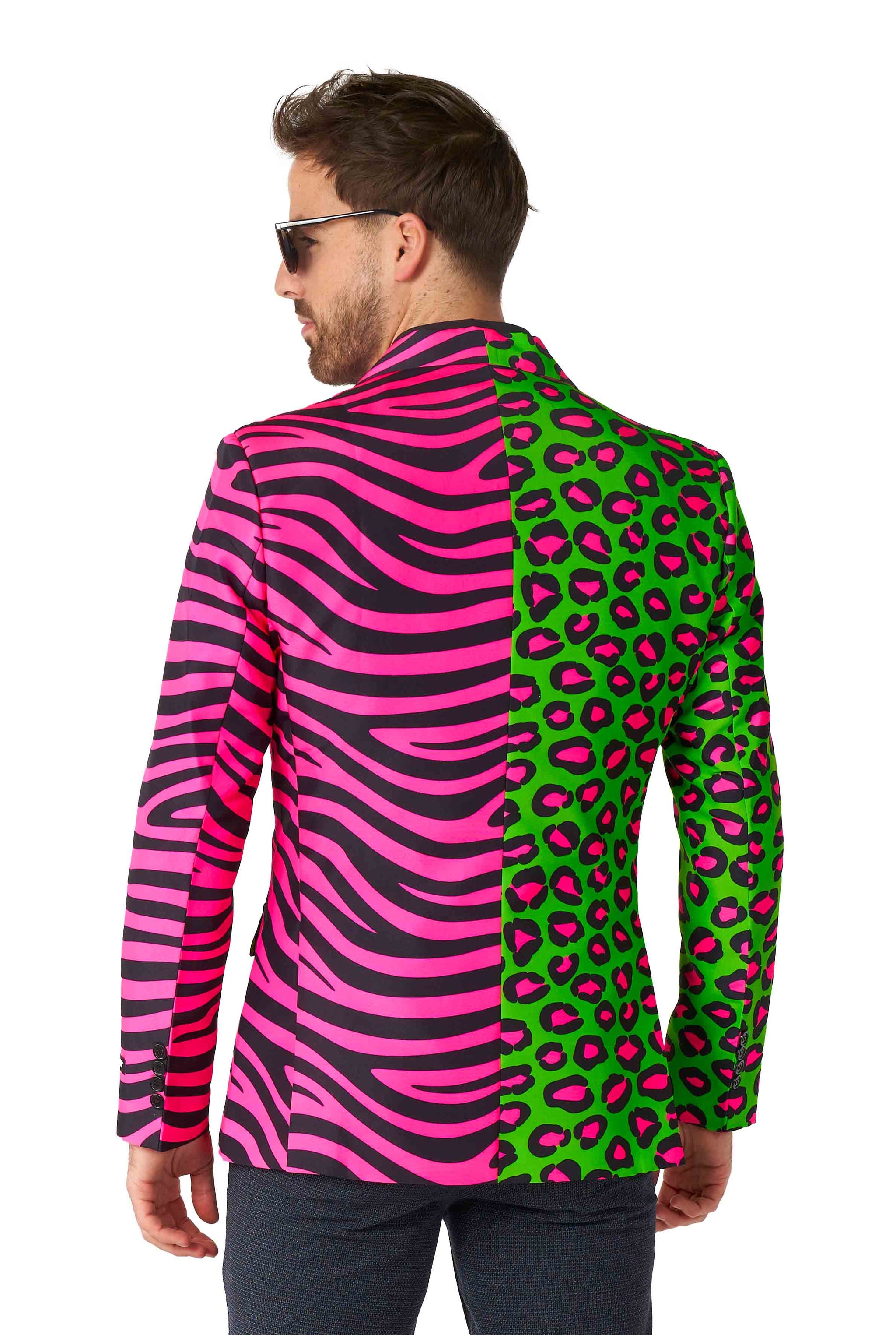 A man wearing the "Party Animal Neon - Party Blazer" by Suitmeister, featuring a unique design with one side showcasing a pink and black zebra pattern and the other side displaying a green and pink leopard print. He is glancing over his shoulder against a white background.