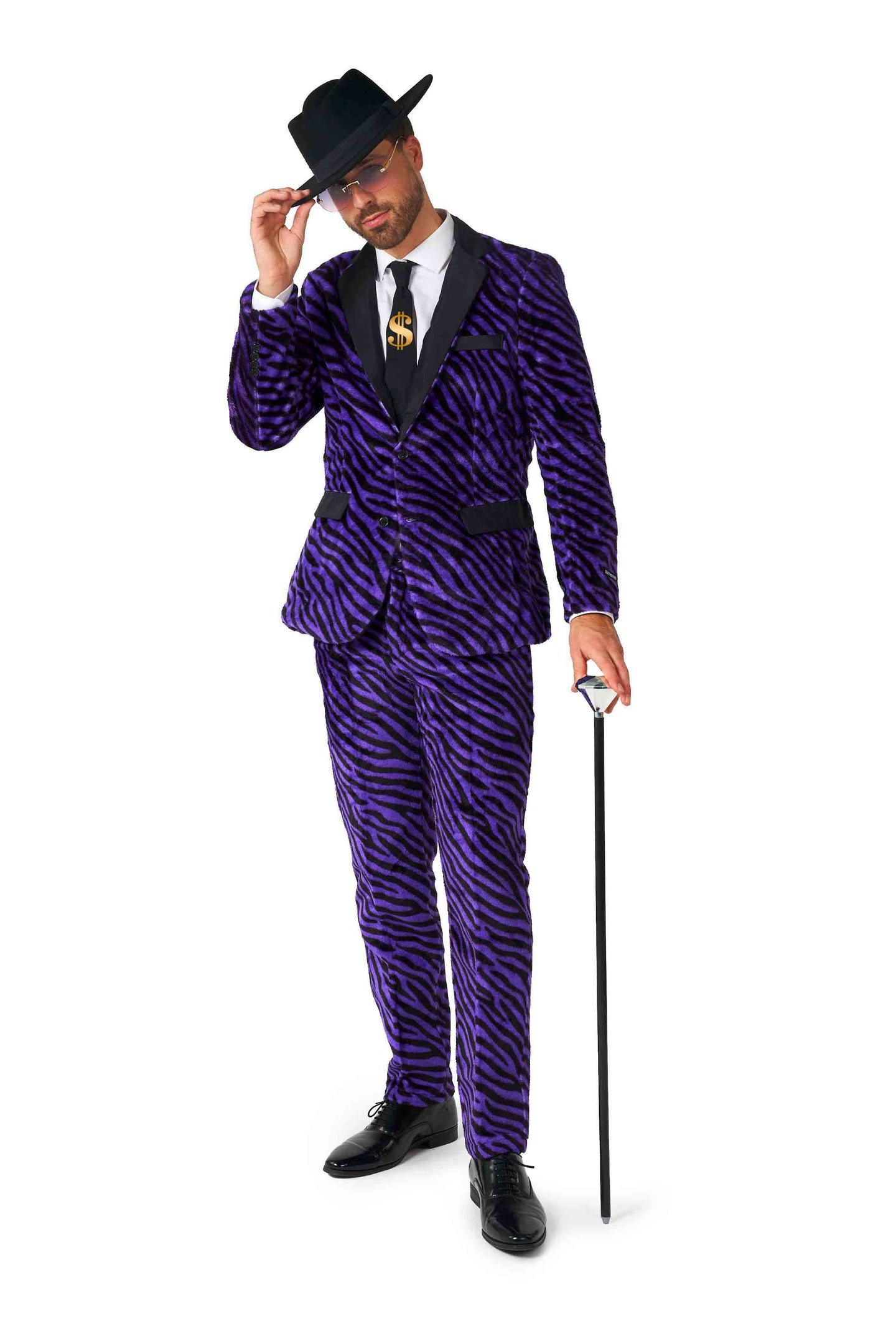 A man dressed in a "Pimp Faux Fur Purple" by Suitmeister, along with a black hat, is holding a black cane. He complements his look with a white shirt, a tie featuring a gold dollar sign, and black shoes against a plain white background.