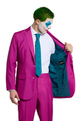 A person wearing the Suitmeister Ruby Red Joker - a vibrant red suit with a teal lining and tie - opens the jacket to display its interior. They have striking green hair and face paint reminiscent of a clown.