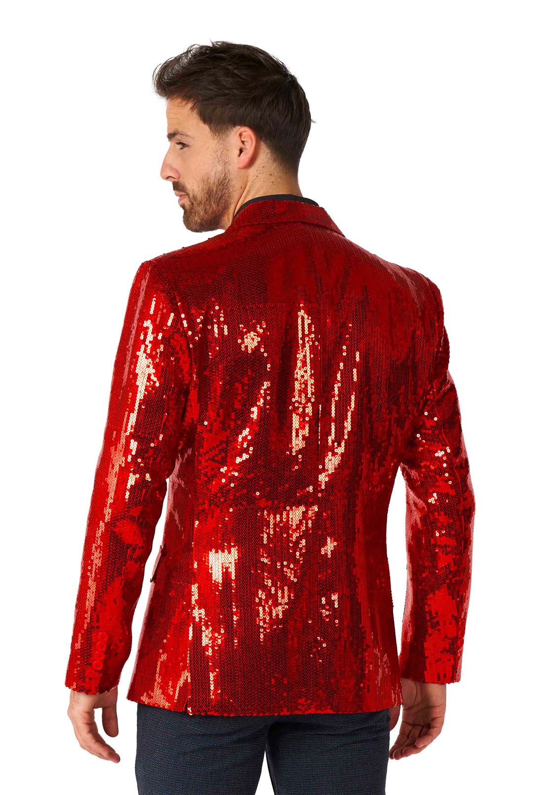 A man with short hair is facing away, wearing the eye-catching Suitmeister Sequins Blazer Red paired with black pants. The blazer shimmers under the light, creating a vibrant and captivating effect.