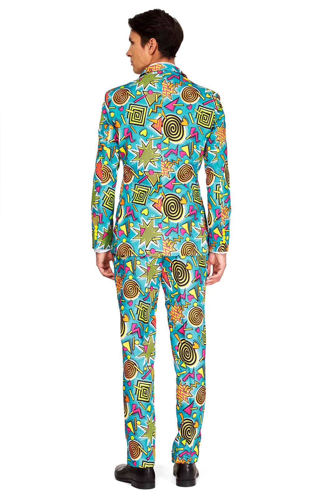 A person is dressed in the Retro Blue 90’s Icons - Carnival Suit by Suitmeister, showcasing a vibrant geometric pattern with stars, spirals, and angular shapes. The suit features a predominantly blue design with lively yellow, orange, and green accents. The individual is photographed from the back.