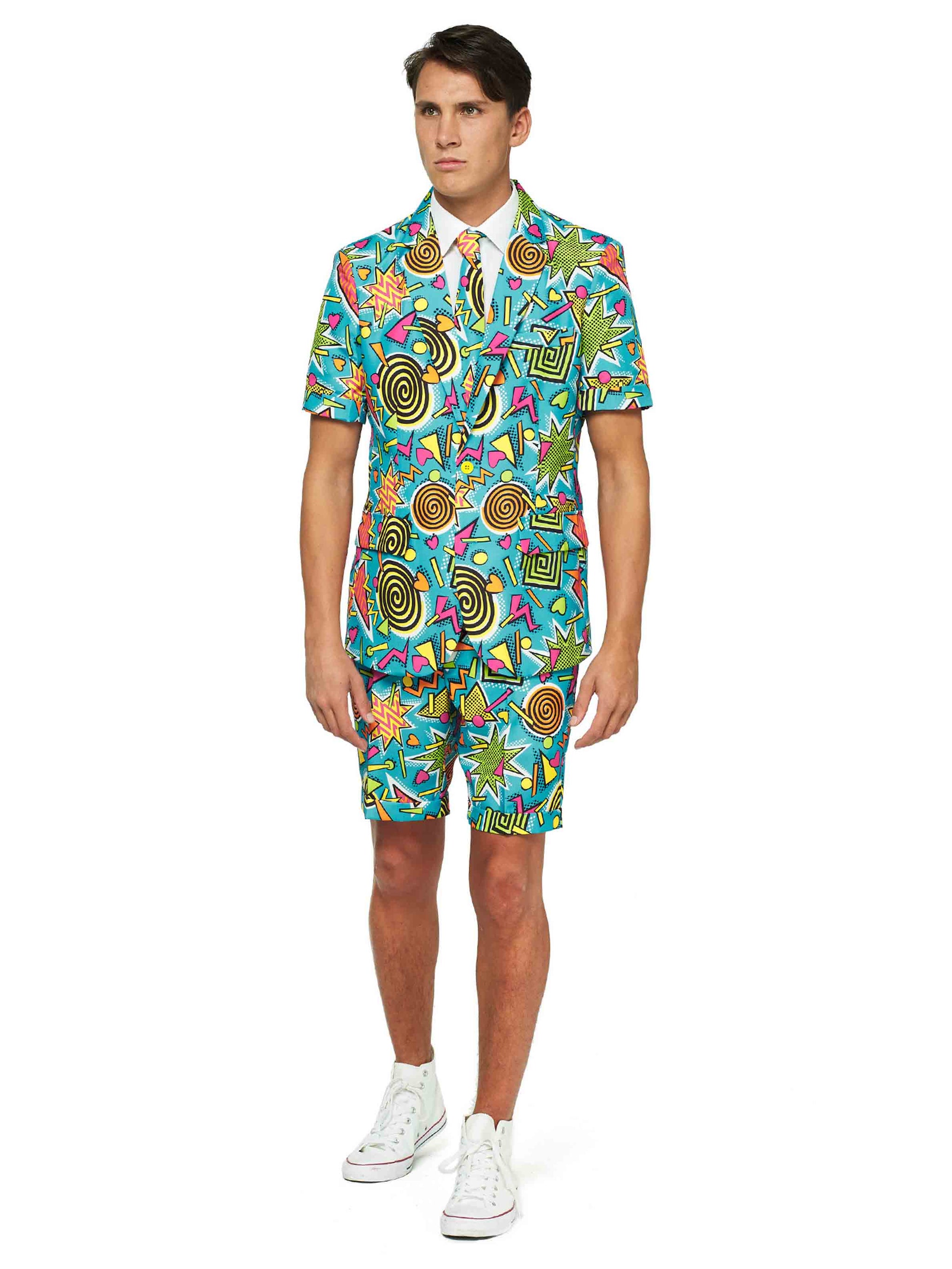 A person dressed in the Retro Blue 90’s Icons - Carnival suit from Suitmeister, featuring a vibrant display of geometric shapes and swirls, stands against a white background. The ensemble consists of a short-sleeve jacket and shorts, complemented by a white shirt, sneakers, and tie.