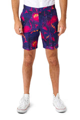 A person dressed in the Retro Neon Navy - Carnival suit by Suitmeister, showcasing a lively tropical sunset pattern with flamingos and palm trees. They pair it with white sneakers and a white shirt against a plain white background.