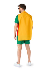 A man stands with his back turned, wearing a vibrant Robin costume from Suitmeister, featuring a striking yellow cape draped over his shoulders. The ensemble comprises a green shirt and shorts, complemented by white sneakers and sunglasses, giving him the appearance of a superhero.