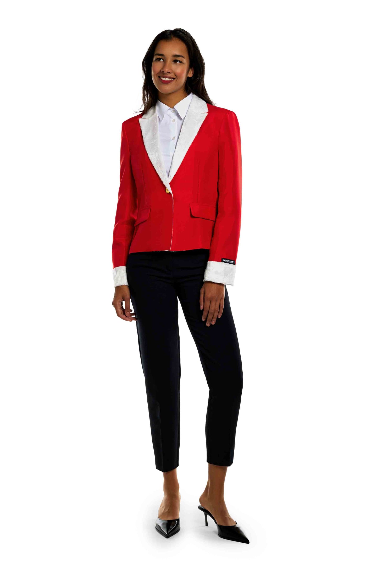 A woman is smiling in the Santa Faux Fur - Christmas blazer from Suitmeister. She pairs the red blazer with white lapels with a crisp white shirt, black pants, and black heels while standing against a white background.