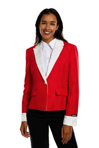 A person smiles while wearing the Suitmeister's Santa Faux Fur - Christmas blazer, featuring red fabric with white faux fur lapels and cuffs, over a white shirt. The person has long dark hair and stands against a plain white background.