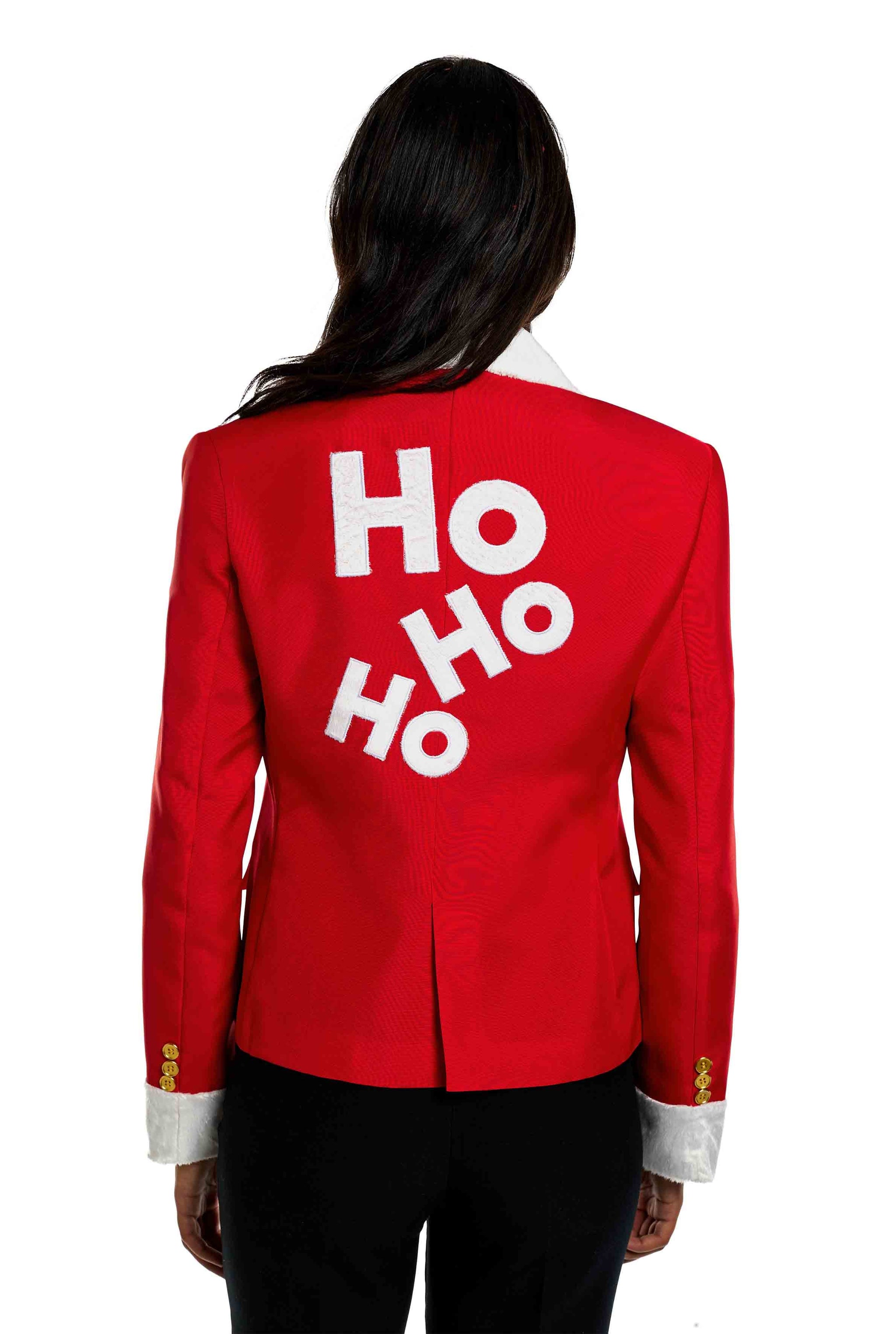 A person is wearing the Suitmeister Santa Faux Fur Christmas blazer, featuring a red design with white letters spelling "HO HO HO" on the back, gold buttons, and white cuffs. The individual is seen from behind against a white background.