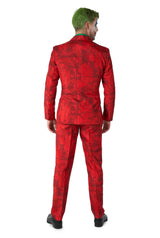 A person with green hair is wearing the Scarlet Joker™ by Suitmeister, a vibrant red suit featuring a comic book pattern. They stand facing away from the camera with their hands relaxed by their sides, complemented by painted face makeup that enhances their distinctive look.