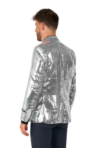 A man wearing the Sequins Blazer Silver by Suitmeister is standing with his back turned, paired with black pants. The blazer is reflective and shiny, catching the light for a dazzling effect.