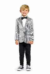 A young boy stands smiling against a plain white background, dressed in Suitmeister's Sequins Silver - Sequin Blazer, complemented by a black bow tie, white shirt, black pants, and black sneakers.