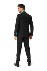 A man with dark hair is standing and facing away, dressed in the Harry Potter Suit - Slytherin™ by Suitmeister, featuring a black suit with green trim and black shoes. The background is white.