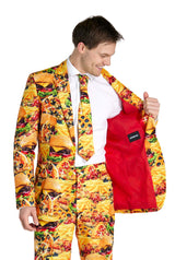 A man sporting the Suitmeister's Snack Master - Carnival suit, adorned with prints of burgers, pizza, and fries, opens his jacket to reveal its vibrant red lining. He is smiling while donning a white shirt and a matching tie.