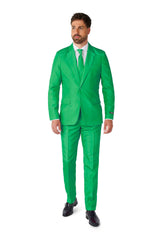 A man dressed in a Solid Green Suit by Suitmeister, paired with a white shirt and green tie, is standing against a plain white background. He has short hair and facial hair and is wearing black shoes.